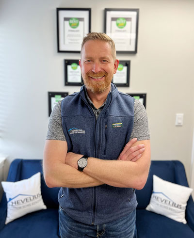 Smiling man in branded vest stands with arms crossed