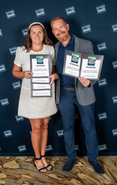 Two award winners holding plaques before branded backdrop