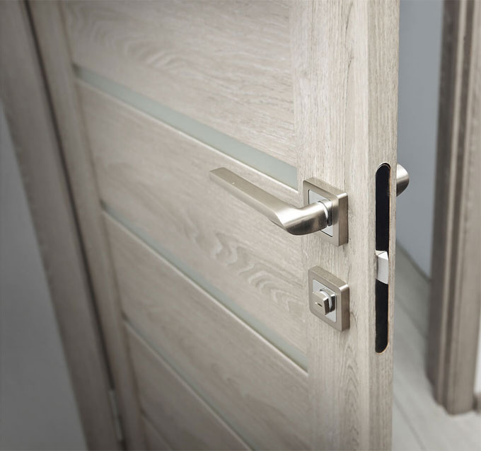 Modern silver door handle on light wood interior door