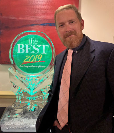 Man in suit poses beside Best 2019 ice sculpture award