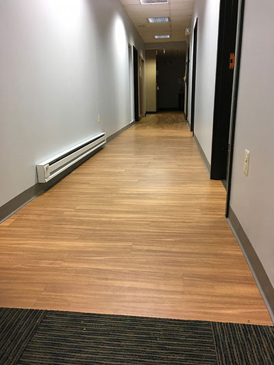 Empty office hallway with wood flooring and gray walls