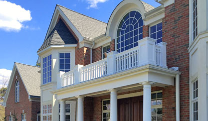Brick mansion facade with white balcony and arched window